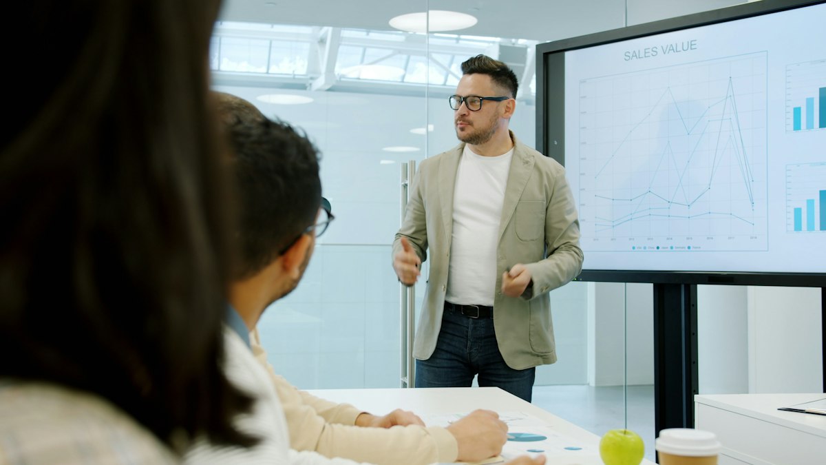 A sales team reviewing performance charts on a large screen in a meeting room